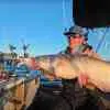 Spencer Bauer holds up a hefty blue catfish aboard his boat on a sunny winter day.